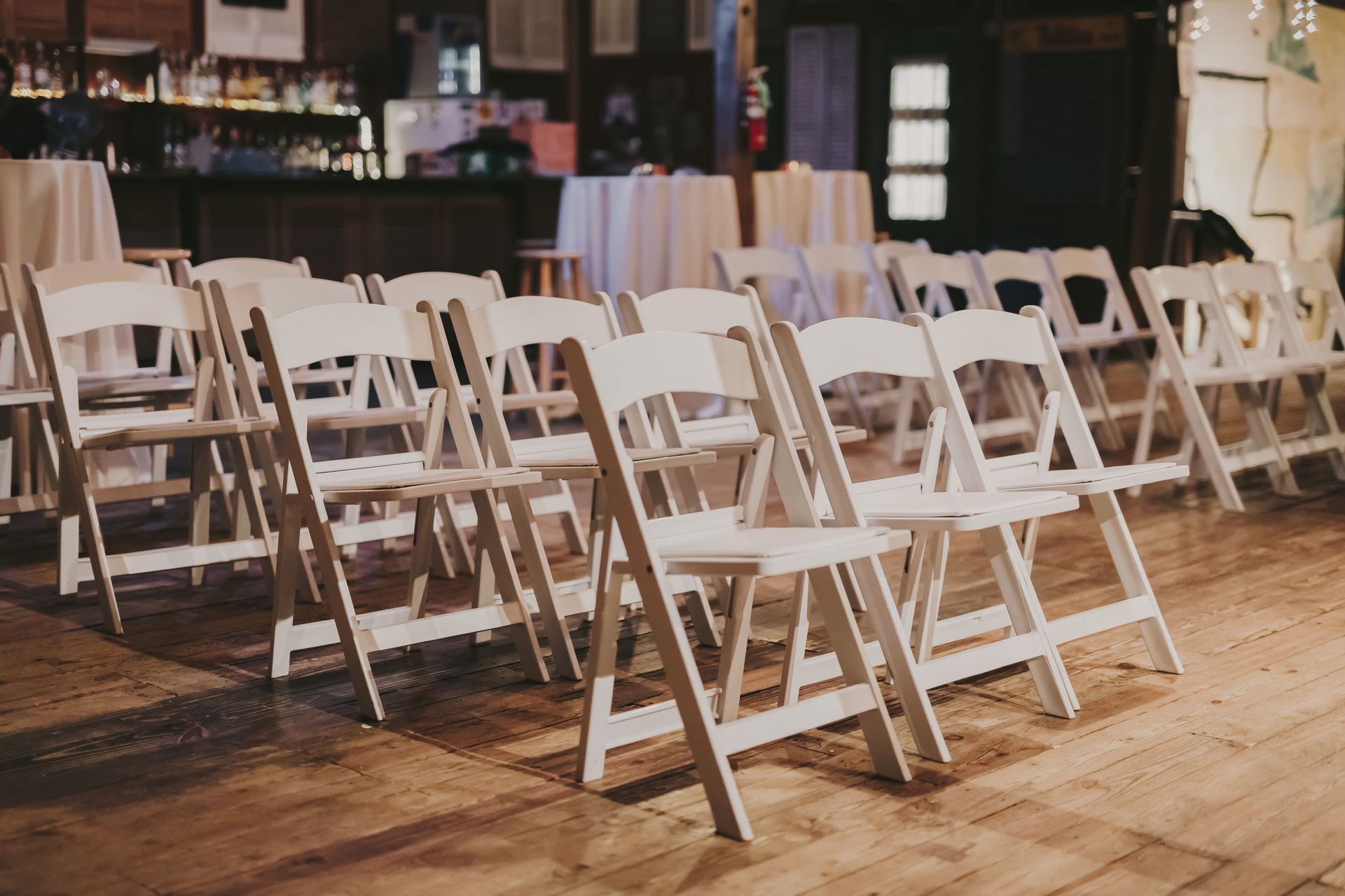 A cozy indoor venue featuring neatly arranged white folding chairs on a wooden floor.