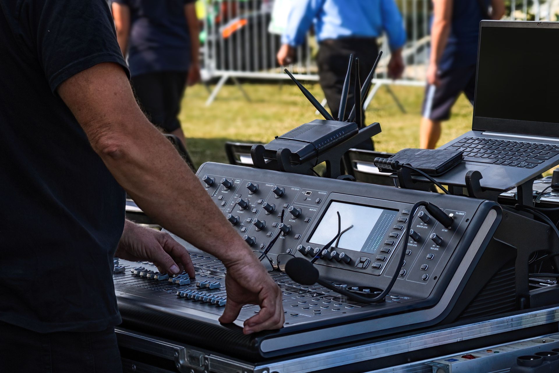 Audio engineer operates sound mixer for outdoor concert setup. Technology and music come together.