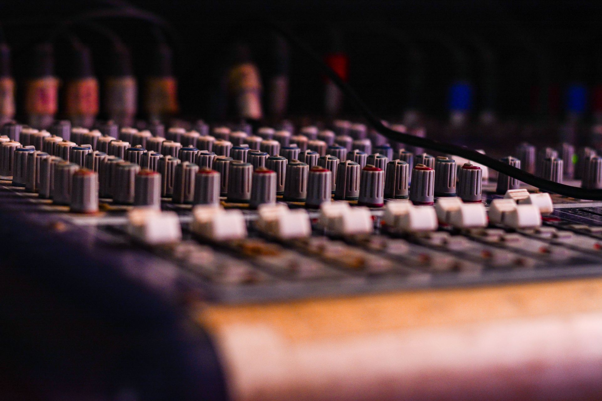 Close-up of a professional audio mixing console with knobs and sliders, essential for music production.