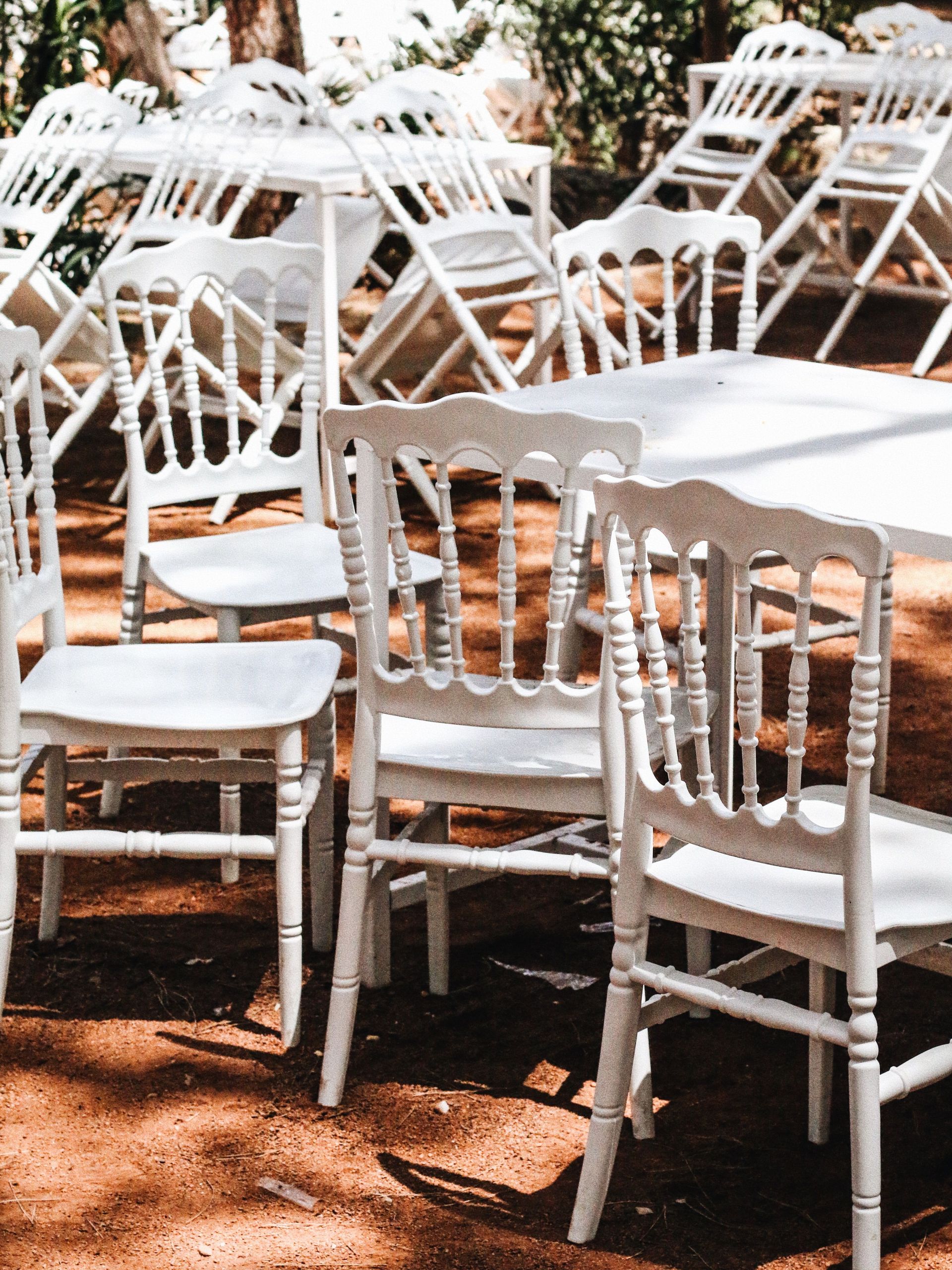 Rustic outdoor scene featuring white chairs arranged for an event on a sunny day.
